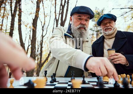 Ritratto di due uomini anziani che giocano a scacchi nel parco di giorno in autunno. Concetto di attività di svago, vecchia generazione Foto Stock