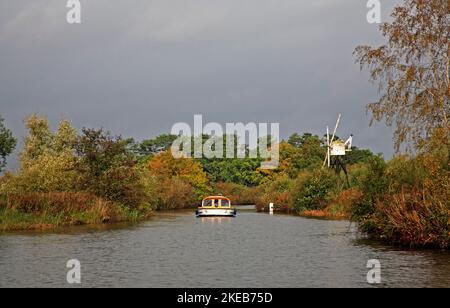 Una vista di un incrociatore sul fiume ANT sul Norfolk Broads passando da Boardmans Mill in autunno da How Hill, Ludham, Norfolk, Inghilterra, Regno Unito. Foto Stock