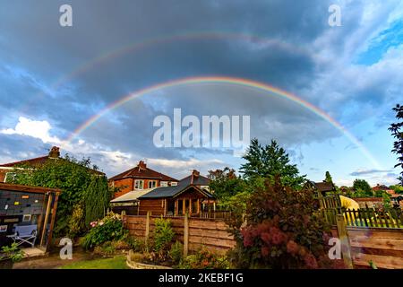 Doppio arcobaleno su case in una proprietà residenziale suburbana, Tameside, Greater Manchester, Inghilterra, Regno Unito Foto Stock