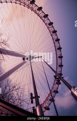 Un colpo a basso angolo dell'occhio di Londra contro un cielo nuvoloso e blu a Londra Foto Stock