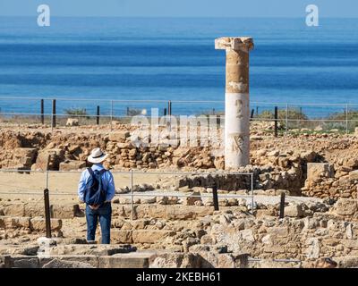 Un visitatore guarda una colonna romana nel sito archeologico di Paphos, Kato Paphos, Cipro. Foto Stock