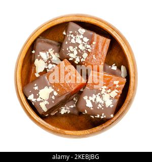 Pezzetti di gelatina di frutta fatti in casa, ricoperti di cioccolato e grattugiate le mandorle, in una ciotola di legno. Dessert di gelee alla frutta dolce dal sapore forte. Foto Stock