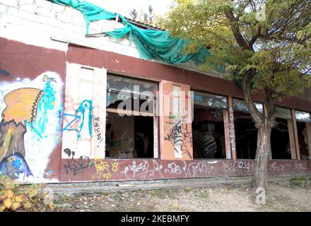 Insolita citysape distrutto edificio rotto finestre blu cielo verde foglie marrone alberi Foto Stock