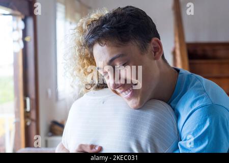 Amante giovane sorridente godere momento forte coccole mamma adulto dopo lunga separazione, madre felice di vedere figlio multi generazionale famiglia riunione, amore e concetto di legame Foto Stock