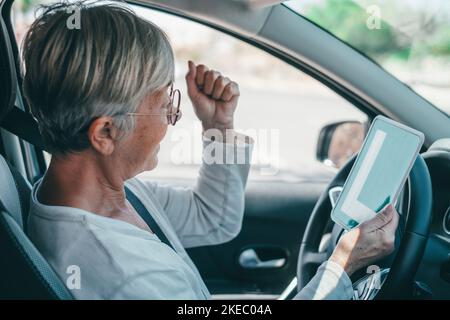 Una donna anziana ottiene il pass per guidare un'auto in età matura. Senior guardando al permesso L nel sedile di guida per celebrare il successo Foto Stock