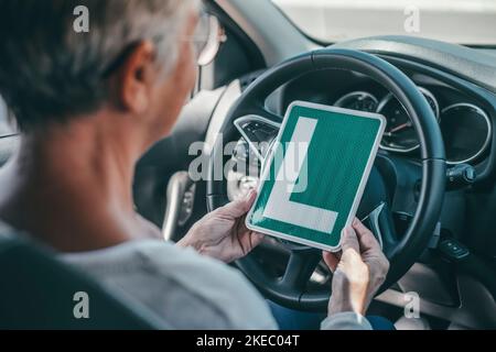 Una donna anziana ottiene il pass per guidare un'auto in età matura. Senior guardando al permesso L nel sedile di guida Foto Stock