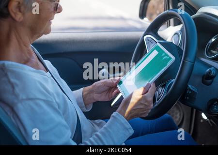 Una donna anziana ottiene il pass per guidare un'auto in età matura. Senior guardando al permesso L nel sedile di guida Foto Stock