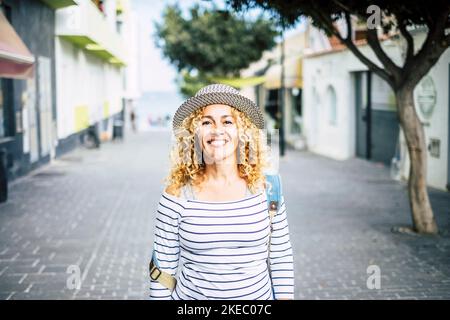 ritratto di giovane bella donna ricci guardando la macchina fotografica mentre cammina per strada alla scoperta e viaggiare nuovi luoghi Foto Stock