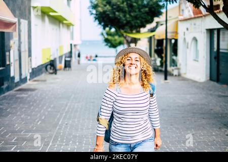 ritratto di giovane bella donna ricci guardando la macchina fotografica mentre cammina per strada alla scoperta e viaggiare nuovi luoghi Foto Stock