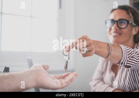 Focus su mazzo di chiavi da casa appartamento in mano di sorridente femmina. Ritratto blurred di realtor professionale sicuro della donna che offre la nuova unità di bene immobile di abitazione al compratore potenziale. Primo piano Foto Stock