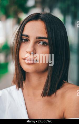 Felice giovane donna alla moda con i capelli corti guardando la macchina fotografica all'aperto. Bella donna soddisfatta con i capelli corti sorridenti mentre fronteggia la macchina fotografica. Ritratto di giovane donna fiduciosa sorridente Foto Stock