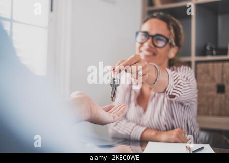 Agente immobiliare donna sorridente che dà le chiavi al compratore dell'appartamento. Proprietario di abitazione che riceve la loro nuova chiave della casa da un agente immobiliare in ufficio. Venditore felice che dà le chiavi della casa al cliente Foto Stock