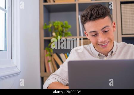 Felice giovane uomo d'affari caucasico sorridente lavorando online guardando il podcast del webinar su laptop e imparare corso di formazione conference call prendere appunti seduti alla scrivania, concetto di elearning Foto Stock