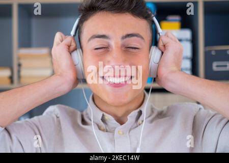 Giovane adolescente tranquillo e spensierato a casa, indossa moderne cuffie wireless, ascolta la musica classica preferita online, sentiti tranquillo e consapevole da solo nel salotto di casa. Foto Stock