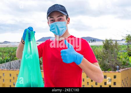 l'uomo aiuta le persone povere dando loro cibo e acqua dentro quarantena per il covid-19 - giovane adulto che lavora da solo indossare una maschera medica e chirurgica per prevenire il coronavirus Foto Stock