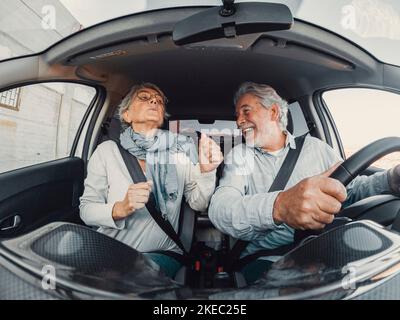 Coppia di due felici danzanti anziani che cantano in vacanza insieme alla guida e alla scoperta di nuovi posti con una macchina. Foto Stock