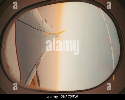 Splendida vista panoramica del tramonto su nuvole e cielo visto attraverso la finestra dell'aereo con ala. Volare e viaggiare. Vista del cielo e dell'ala dall'interno della finestra dell'aereo Foto Stock