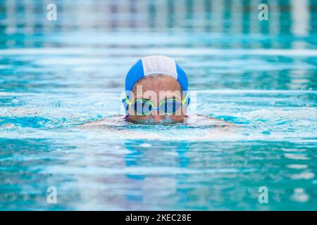 primo piano di una donna matura che nuota in una piscina da sola - ritratto dell'anziano attivo che fa l'esercitazione all'aperto Foto Stock