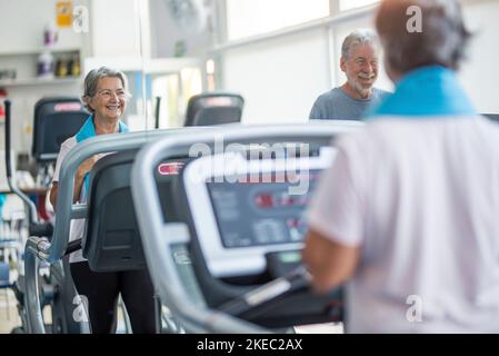 coppia di due anziani felici e installabili che fanno l'esercitazione dentro la palestra insieme in esecuzione sul tapis roulant - attivo stile di vita Foto Stock