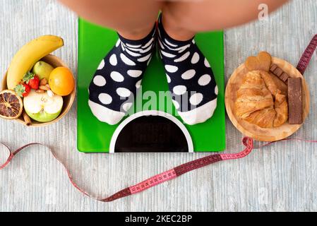 primo piano e ritratto di gambe e piedi che pesano su una bilancia per vedere se ha perso peso dopo uno stile di vita sano mangiare frutta Foto Stock