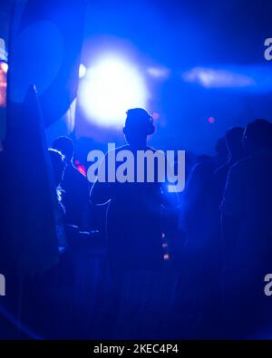 Una silhouette di un ragazzo che indossa le cuffie al festival di Vienna in discoteca silenziosa con luce blu, Austria Foto Stock