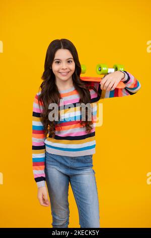 Skater ragazza hipster teen con skateboard su sfondo isolato. Tendenza estiva per bambini, stile adolescente urbano. Felice adolescente, emozioni positive e sorridenti Foto Stock