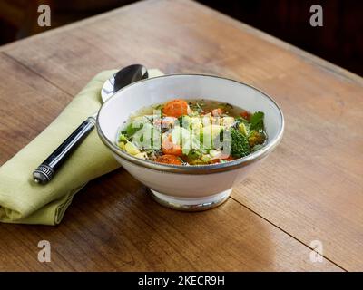 cucina ayurvedica, zuppa di verdure in ciotola bianca con bordo in argento su tavolo in legno Foto Stock