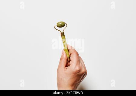 una mano che tiene una banana verde che è stata sbucciata a metà per renderla simile ad una mela Foto Stock