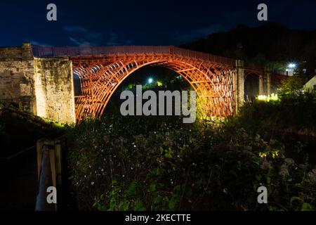 Vista notturna del Ponte di ferro sul fiume Severn, illuminato dalle luci. Shropshire, Inghilterra. Foto Stock