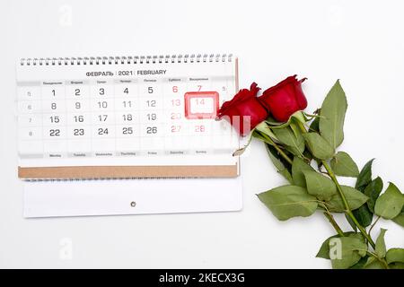 una rosa rossa accanto a un calendario su sfondo bianco con la data cerchiata da un timbro di gomma che dice buon san valentino Foto Stock