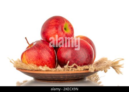 Diverse mele rosse mature su un piatto di legno, macro, isolate su fondo bianco. Foto Stock