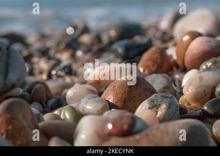 Massi arrotondati bagnati di diverse dimensioni e colori su una spiaggia in un'atmosfera di tranquillità e pace Foto Stock