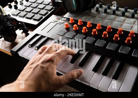 La mano del musicista su un sintetizzatore moderno, tastiera midi. Studio di registrazione. Musicista, compositore, ingegnere del suono. Lavoro sonoro, podcast. Equi musicali moderni Foto Stock