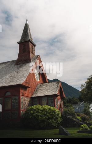 Un colpo verticale di San Pietro dalla Chiesa episcopale del mare circondata da verdi cespugli lussureggianti sotto il cielo nuvoloso, Alaska Foto Stock