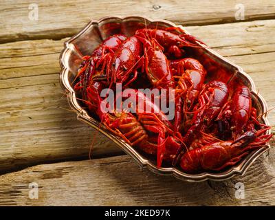 Elegante composizione culinaria. Piatto con appetitosi gamberi bolliti su un semplice tavolo di legno. Primo piano. Stile country. Non ci sono persone nella foto Foto Stock