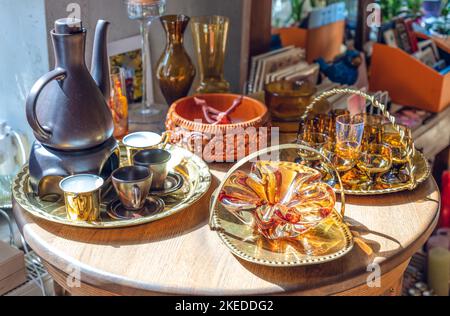 Vetreria marrone vintage su utensili in metallo. Tavolo di legno. Luce solare. Foto Stock