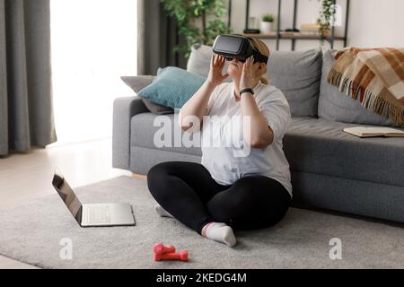 Donna in sovrappeso che utilizza il visore VR Foto Stock