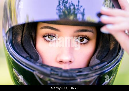 Primo piano sugli occhi di Teenage femmina Adjusting Dirt Bike casco | Moto Foto Stock