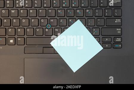 Tastiera del computer portatile con una nota adesiva vuota blu Foto Stock