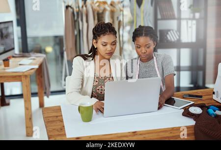 Theyre che lavora su un nuovo marchio. Due giovani stilisti che lavorano su un laptop. Foto Stock