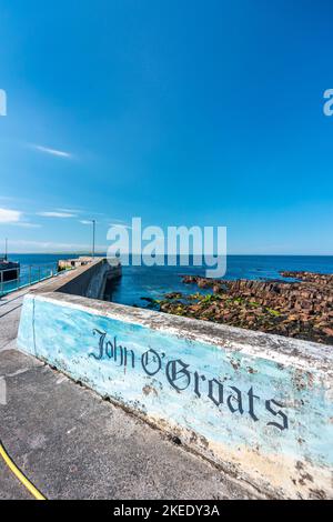 Adagiato contro il cielo limpido, blu profondo e nuvoloso di mezza estate presso il molo dei traghetti, la costa rocciosa oltre, in piena luce del sole. Foto Stock