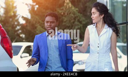 Il venditore afro-americano mostra le automobili al cliente eccitato Foto Stock