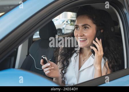 Donna dai capelli neri parla con un amico di auto al telefono Foto Stock