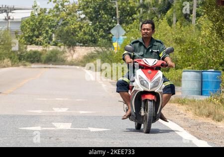 BANGKOK, THAILANDIA, 01 2022 GIUGNO, Un uomo cavalca in moto su una strada rurale Foto Stock