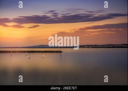 Una bella scena al tramonto sul grande mare con anatre e terra all'orizzonte Foto Stock
