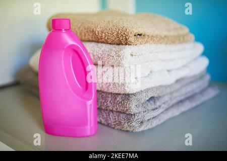 Pulito e fresco. Una bottiglia di detergente accanto a una pila di asciugamani piegati. Foto Stock
