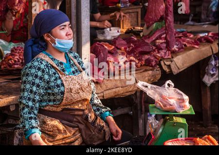 Un fornitore cambogiano di carne cruda che indossa una maschera facciale e utilizza una bilancia durante la pandemia COVID. Mercato di Kandal, Phnom Penh, Cambogia. © Kraig Lieb Foto Stock