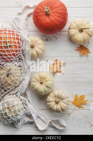 Vista dall'alto composizione autunnale con zucche in borsa a rete su sfondo di legno Foto Stock