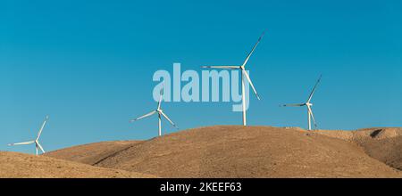 Turbine eoliche multiple in piedi su una collina all'alba e che generano elettricità Foto Stock