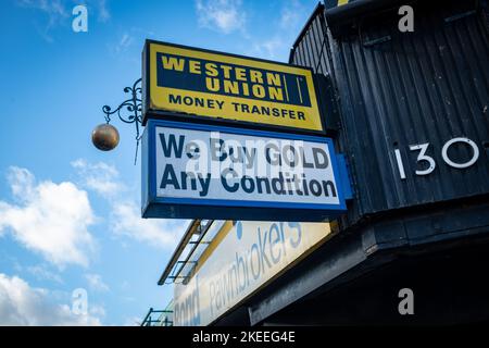 Londra - Novembre 2022: Western Union e noi compriamo segni d'oro al di fuori di un vecchio pawnbroker a West Ealing Foto Stock